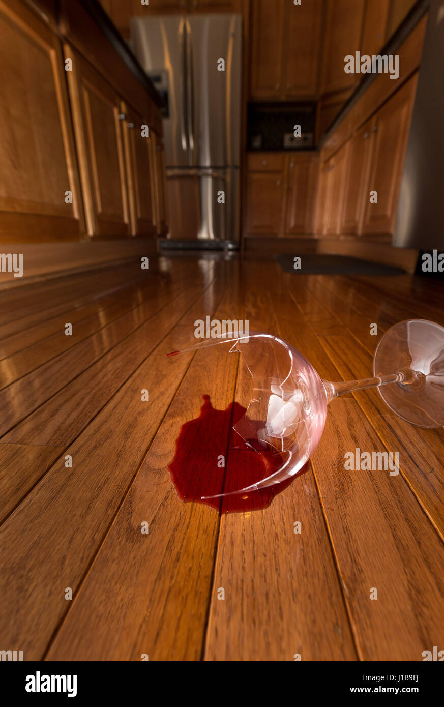Rotto il vetro di vino sul pavimento della cucina moderna - la violenza domestica concept Foto Stock
