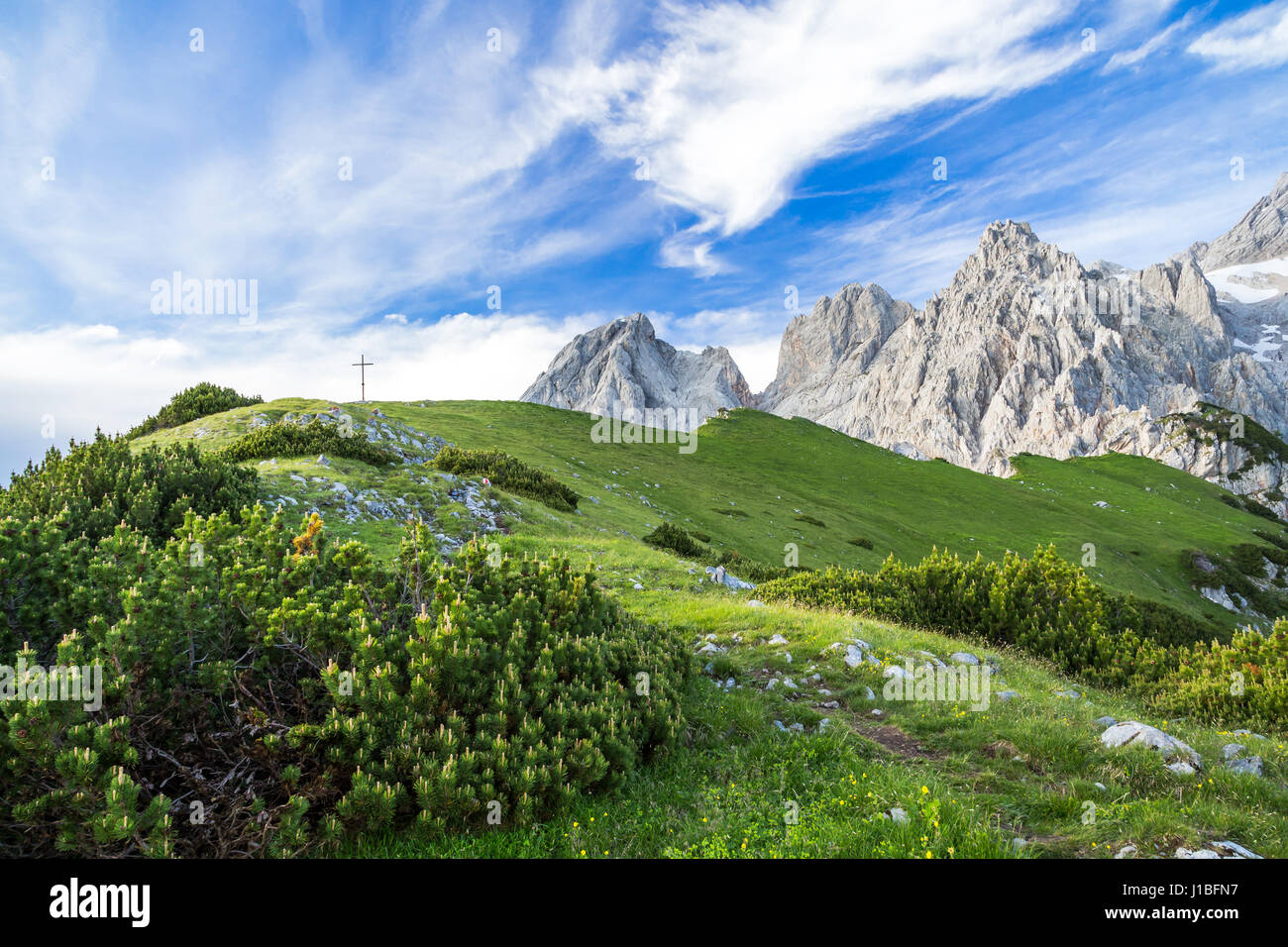Una montagna verde top con top cross contro lo sfondo di pungenti pietra calcare montagne in estate Foto Stock