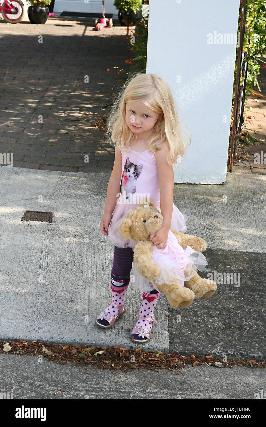 Bimba bionda bambino mentre tiene il suo orsacchiotto di peluche vestito in tutus corrispondenti Foto Stock