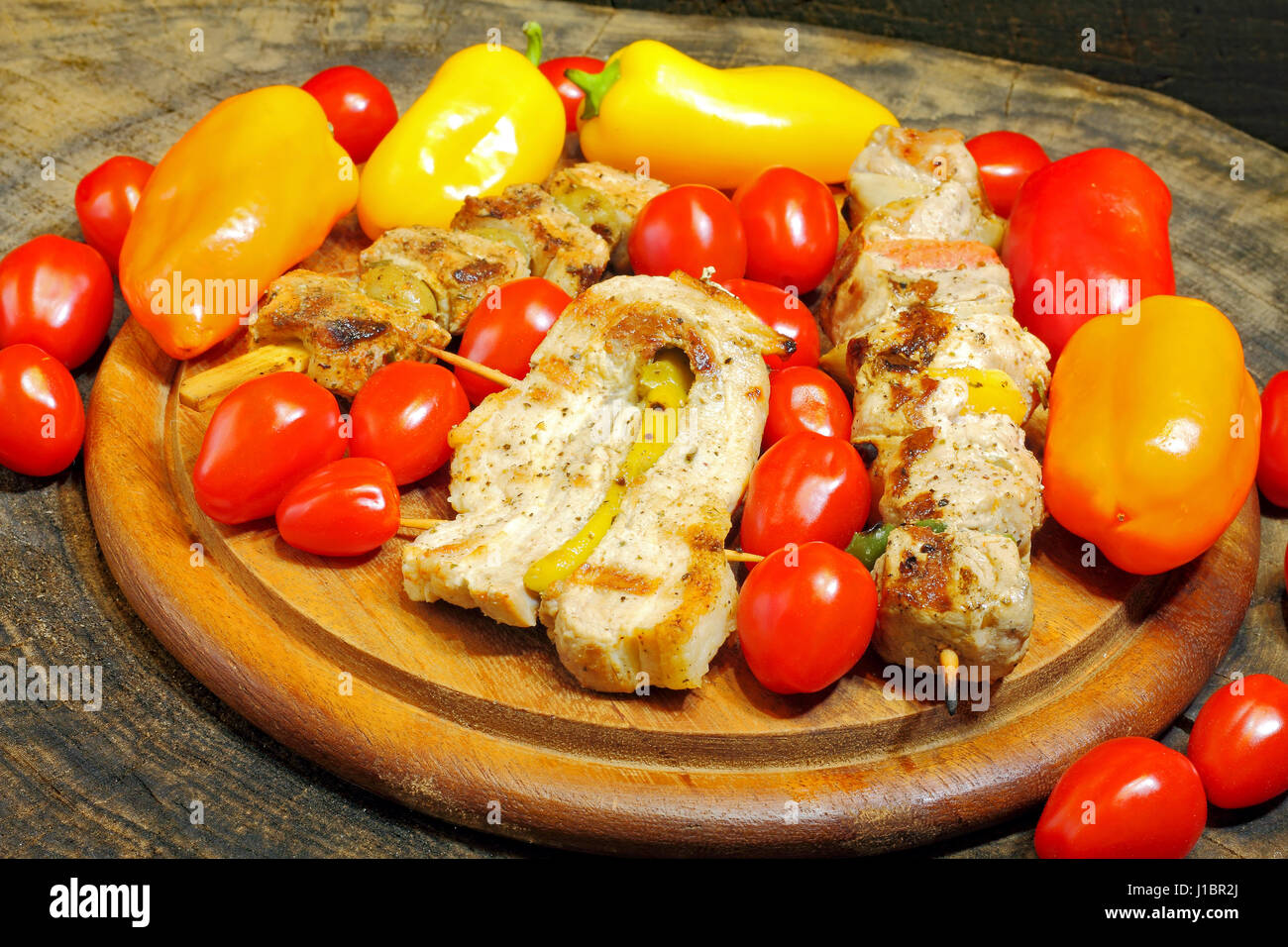 Grigliata di spiedini di carne con verdure su una tavola di legno Foto Stock