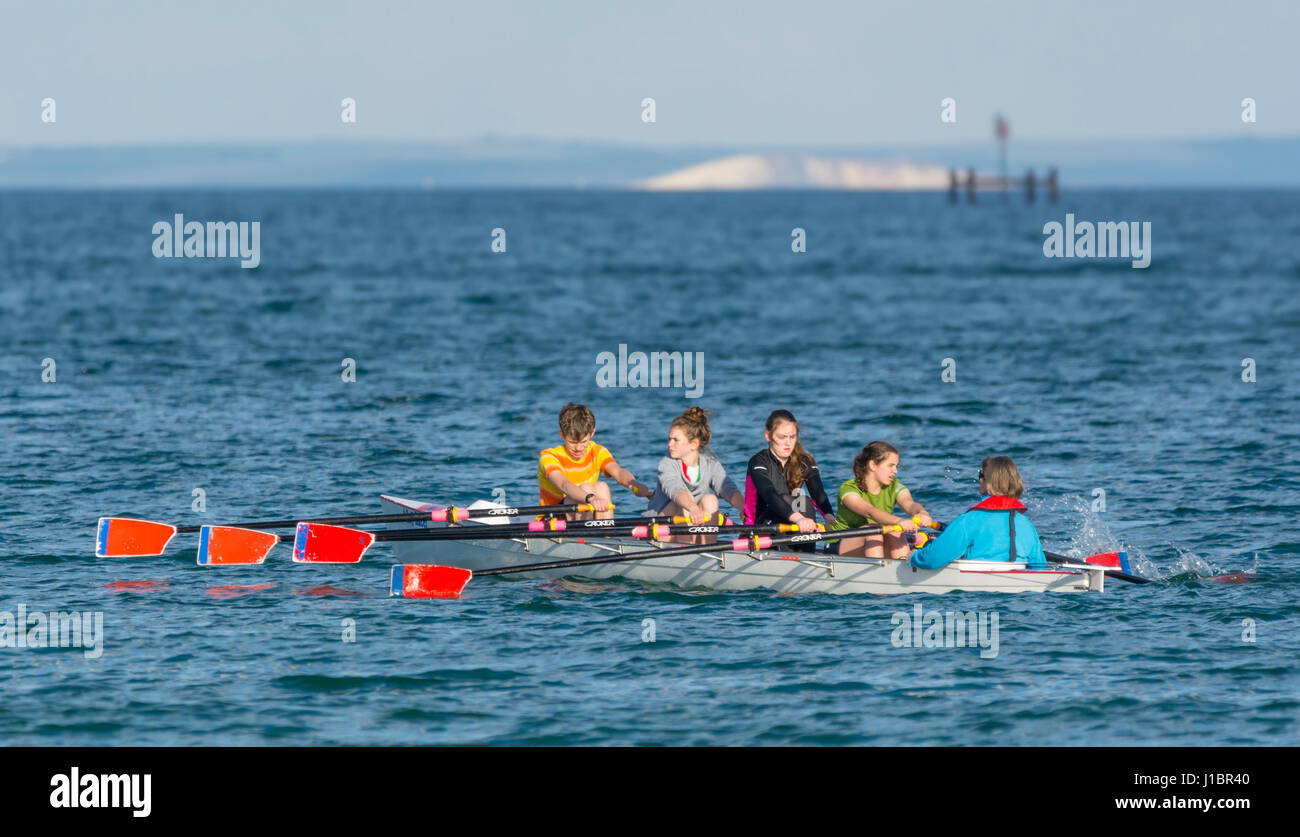 4 giovani donne equipaggio di canottaggio in un Coxed Quad (4X+) scull barca a remi con un Cox, canottaggio sul mare. Foto Stock