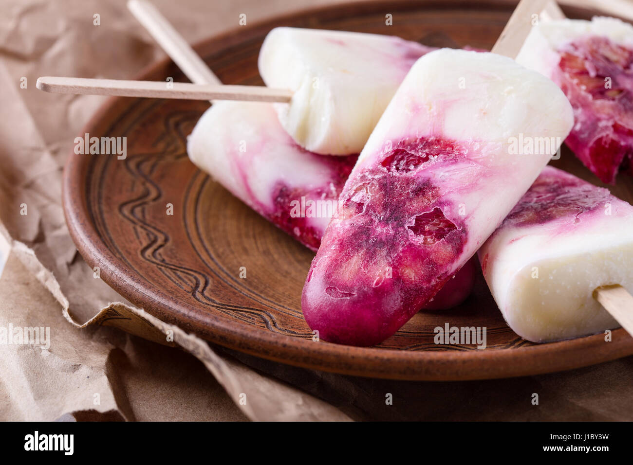 Yogurt fatto in casa ice pops decorate con sangue fettine di arancia onceramic piastra oltre rustico di colore grigio chiaro nella tabella Foto Stock