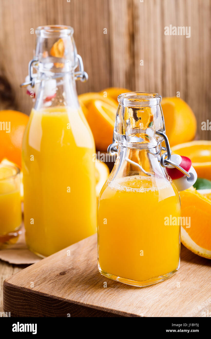 Spremuta di arancia fresca in bottiglie contro lo sfondo di agrumi freschi Foto Stock