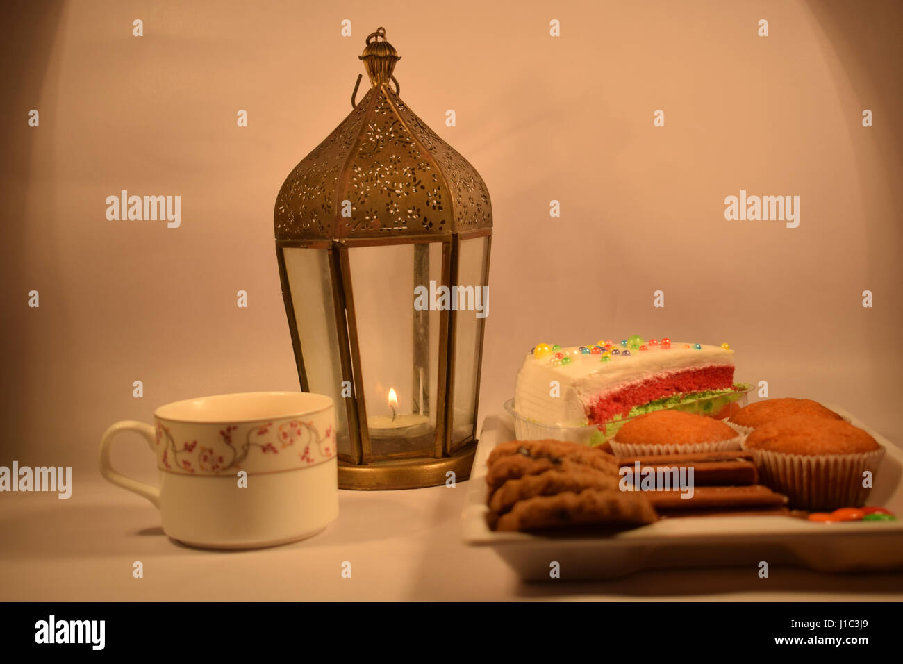 Una tazza di tè con biscotti, candela nella lampada. Foto Stock