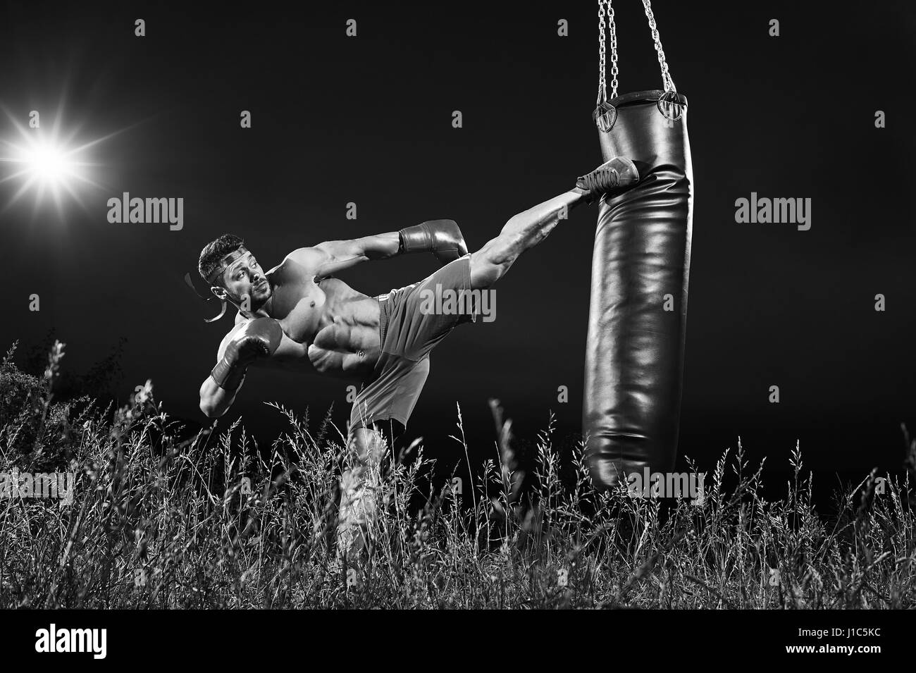 Foto in bianco e nero di un boxer maschio di formazione con un sacco da boxe ou Foto Stock