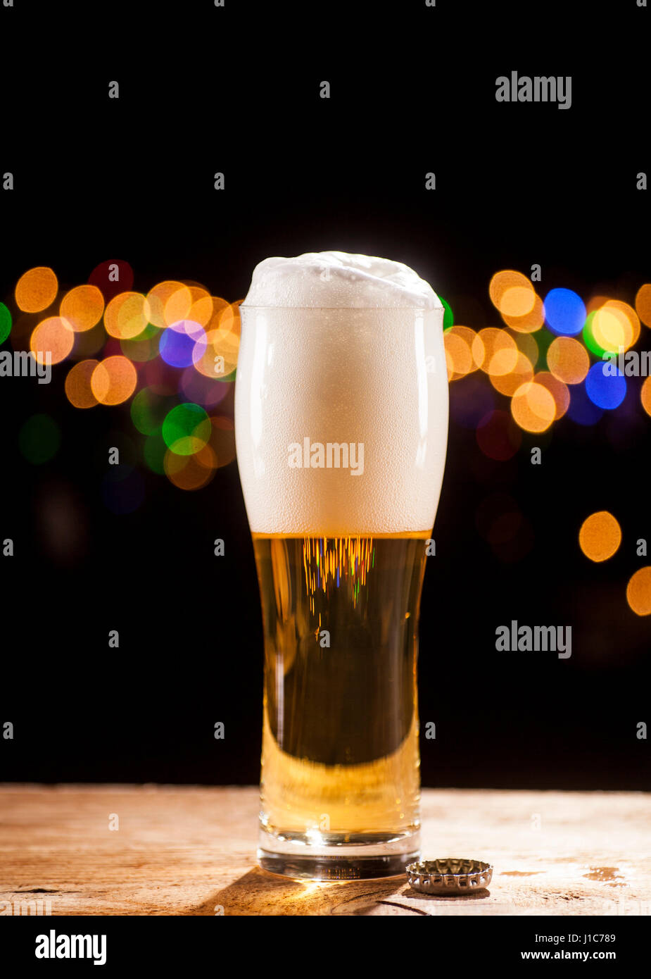 Bicchiere di birra sul tavolo di legno e le luci della barra sfondo. Foto Stock Bicchiere di birra sul tavolo di legno e le luci della barra sfondo. Foto Stock