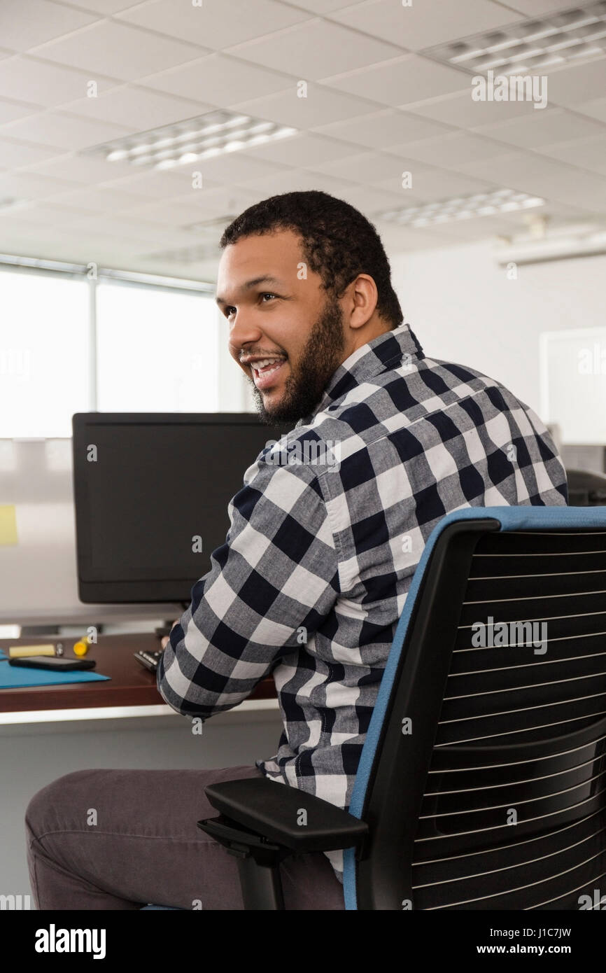 Sorridente razza mista uomo utilizzando computer in ufficio Foto Stock