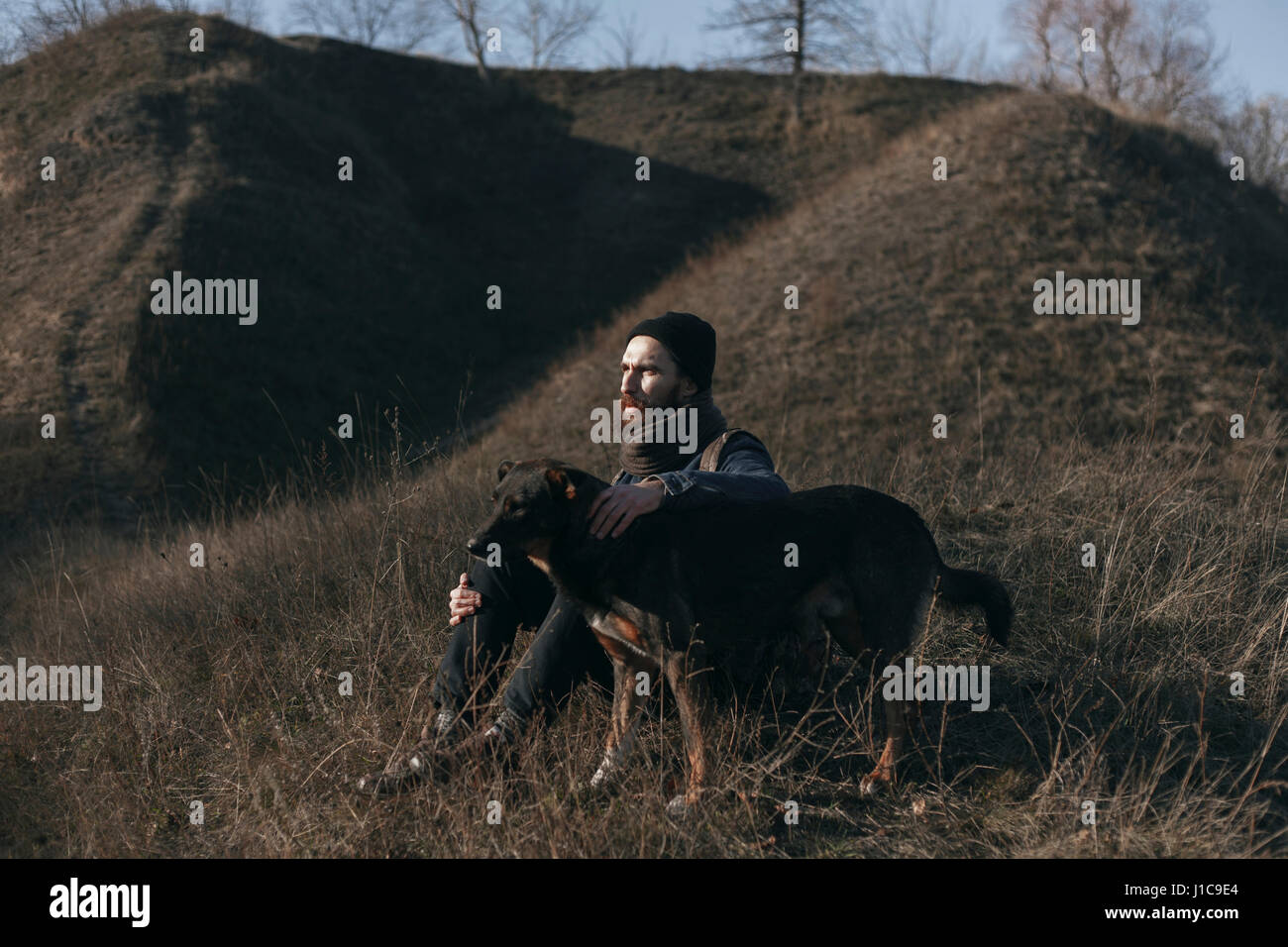 Uomo caucasico seduto sulla collina petting cane Foto Stock
