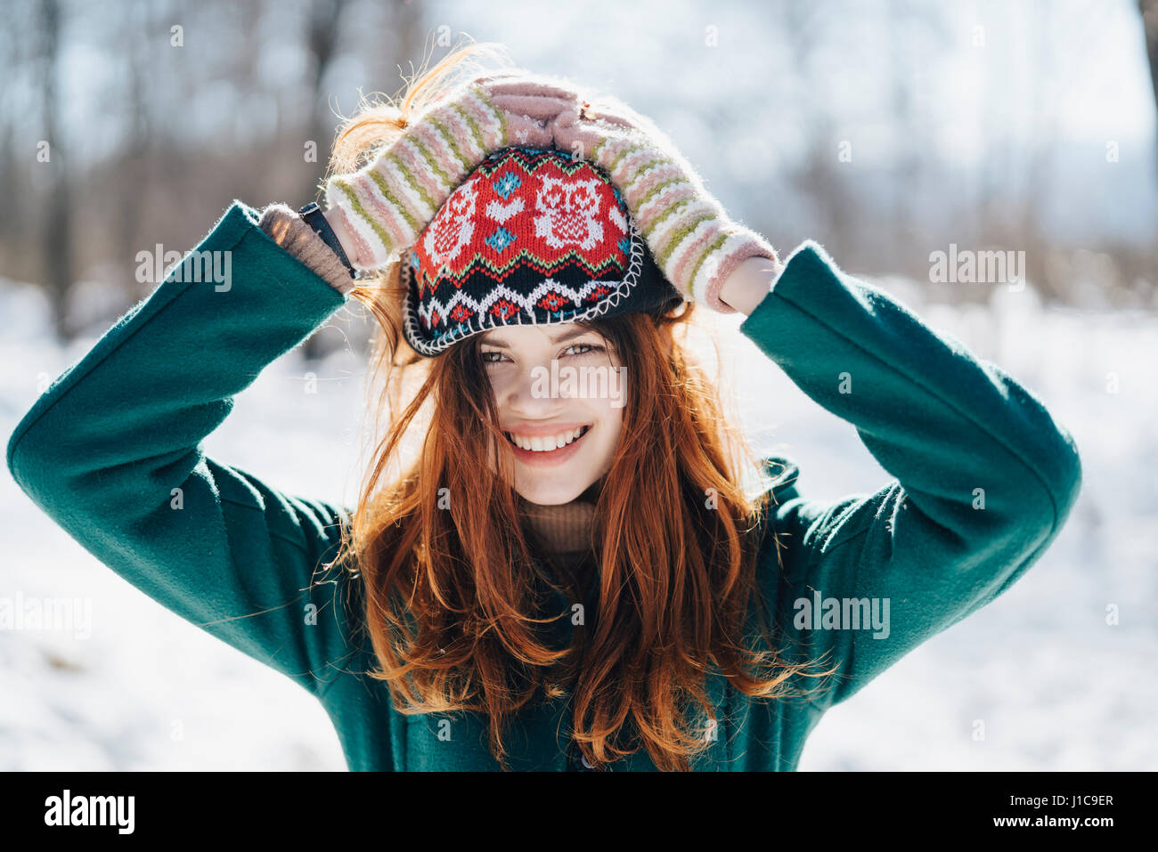 La donna caucasica holding hat sulla testa in inverno Foto Stock