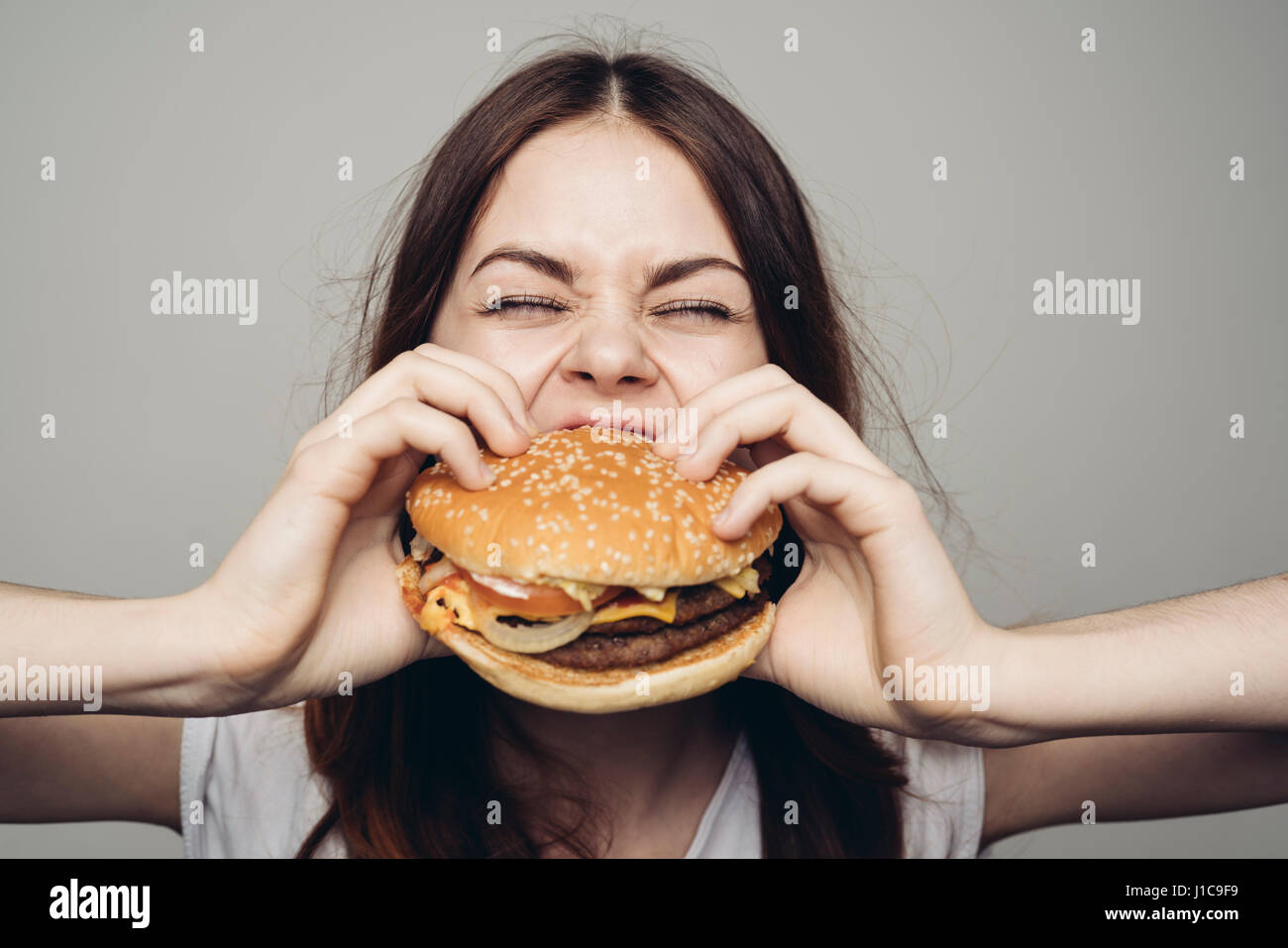 La donna caucasica mangiare cheeseburger Foto Stock