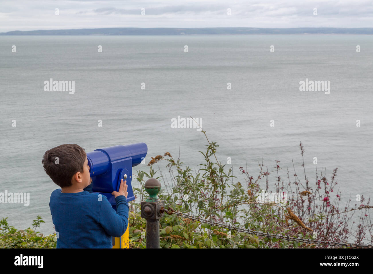 Un ragazzino guardando attraverso il telescopio,Devon, Inghilterra Foto Stock