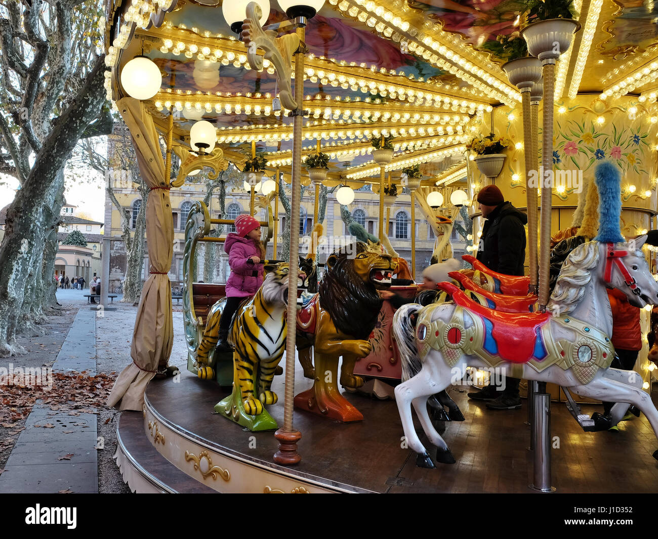 La giostra - Molto carino bambina indossa un lilla down jacket e carny rotonda - merry-go-round presso il quartiere fieristico di Lucca, Toscana, Italia, Europa Foto Stock