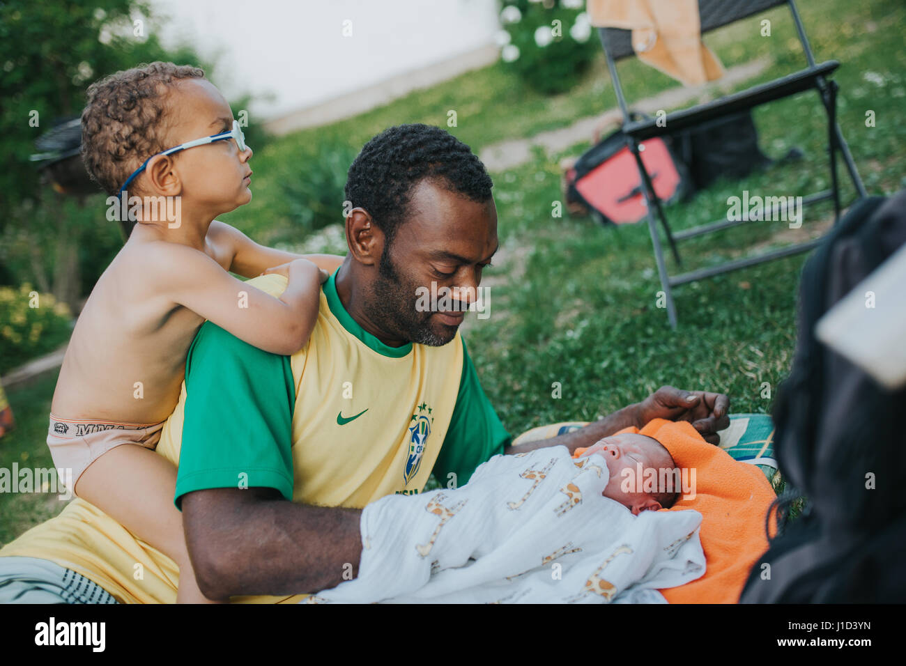 Padre gioca con i suoi due figli in giardino Foto Stock