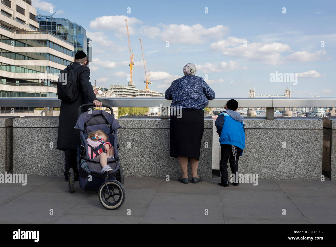 Una famiglia ebraica di guardare la vista del fiume Tamigi e nella distanza, Tower Bridge, dal London Bridge, il 19 aprile, nella città di Londra Foto Stock