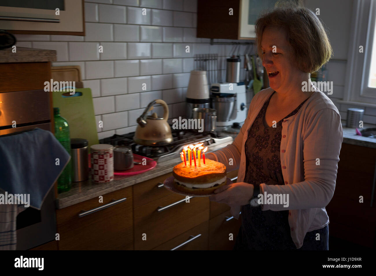 Una madre porta in sé il figlio della torta di compleanno nella cucina di casa propria, il 31 marzo 2017, a Londra, in Inghilterra. Foto Stock