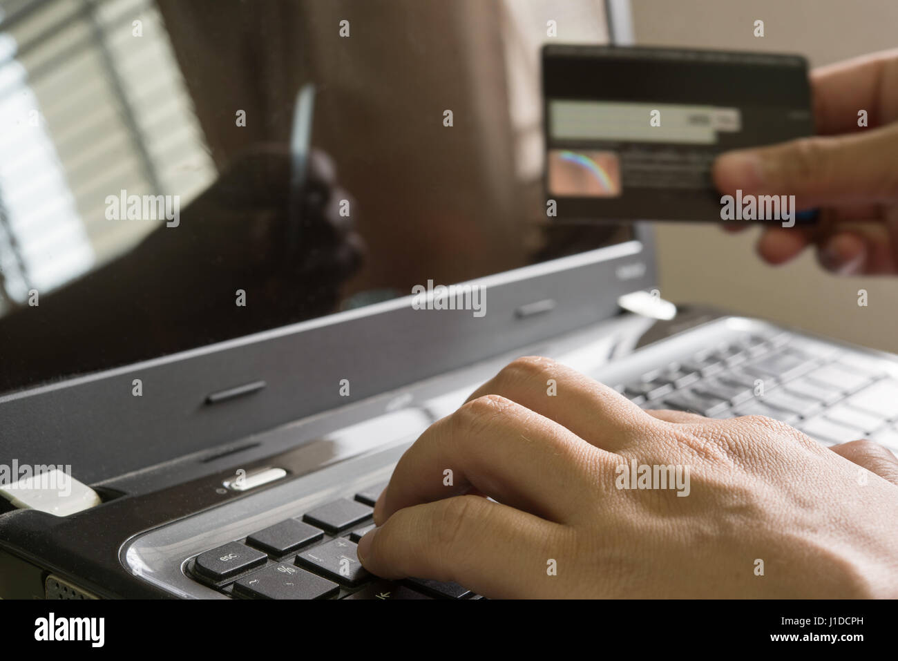 La mano in possesso di una carta di credito e utilizzando il laptop per shoping on-line su internet a casa, IOT internet delle cose concept Foto Stock