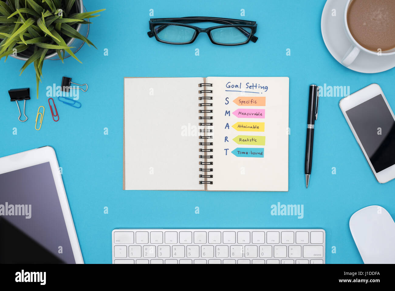 La fissazione degli obiettivi Smart su notebook con forniture per ufficio, computer, occhiali e la tazza di caffè blu su sfondo scrivania, il successo aziendale concept Foto Stock