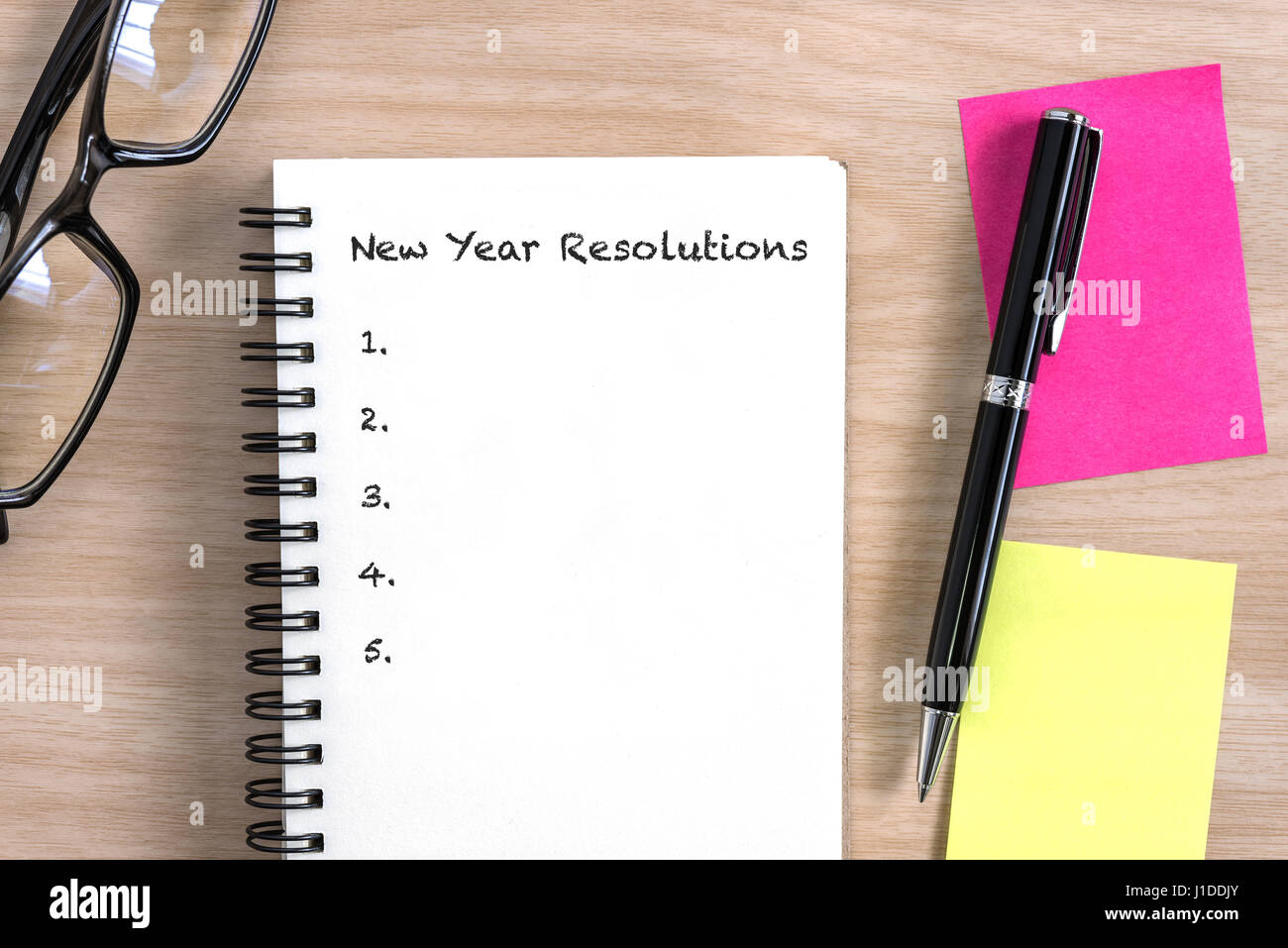 Propositi per l'anno nuovo concetto con notebook aperto, penne colorate nota adesiva e occhiali sulla scrivania in legno Foto Stock