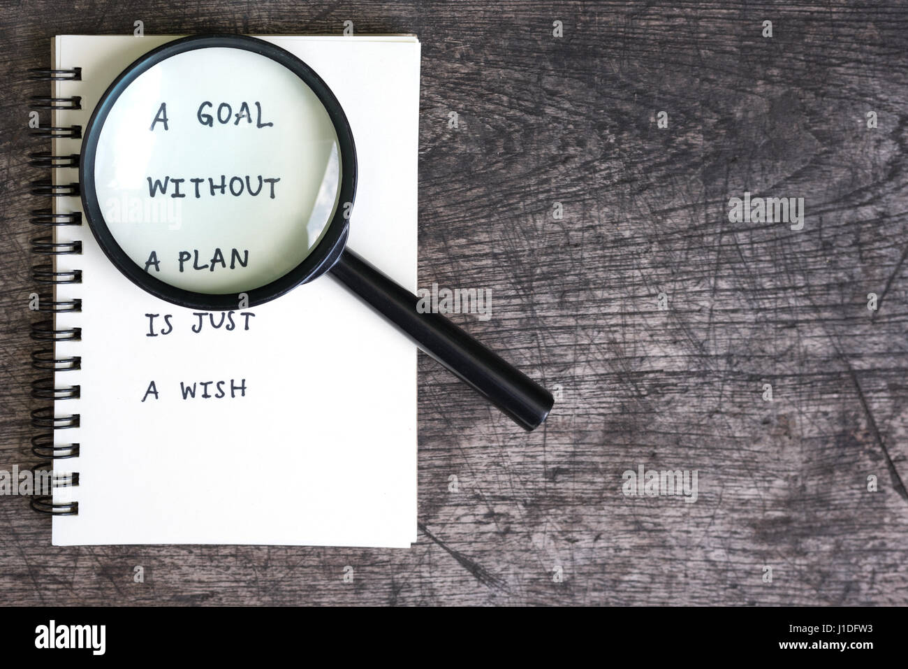 Un obiettivo senza un piano è solo un desiderio motivazionali di scrittura a mano su un notebook aperto con lente di ingrandimento Foto Stock