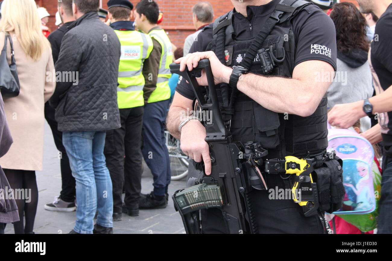 Armato di un Galles del Sud police officer sovrintende la folla durante un 21-gun salutate in onore di Sua Maestà la Regina Elisabetta II per il compleanno, al di fuori della National Assembly for Wales, la Baia di Cardiff, Galles, UK. 21 Aprile 2017 Foto Stock