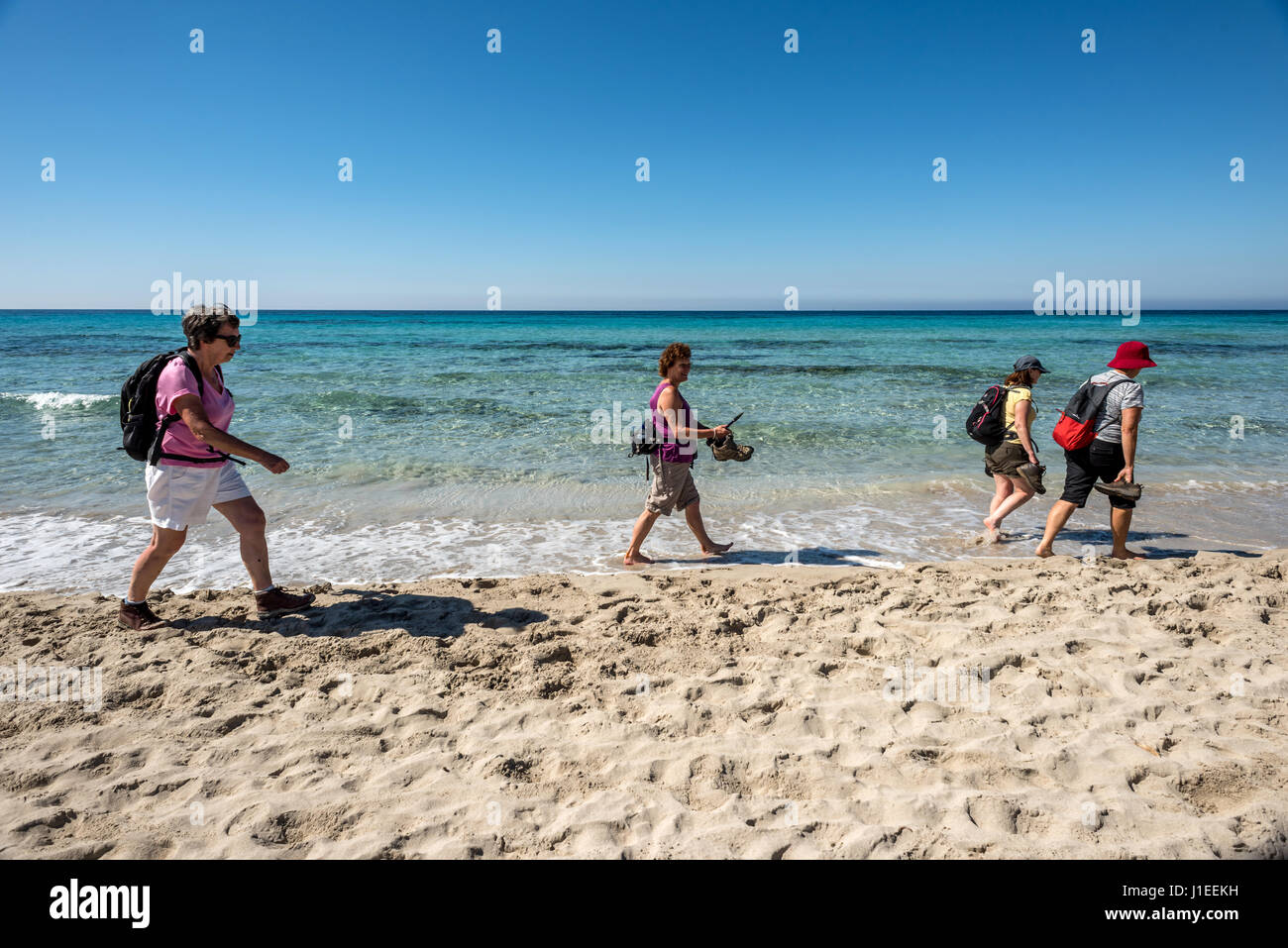 Walkers sulla spiaggia di Santo Tomas nel sud di Menorca Foto Stock