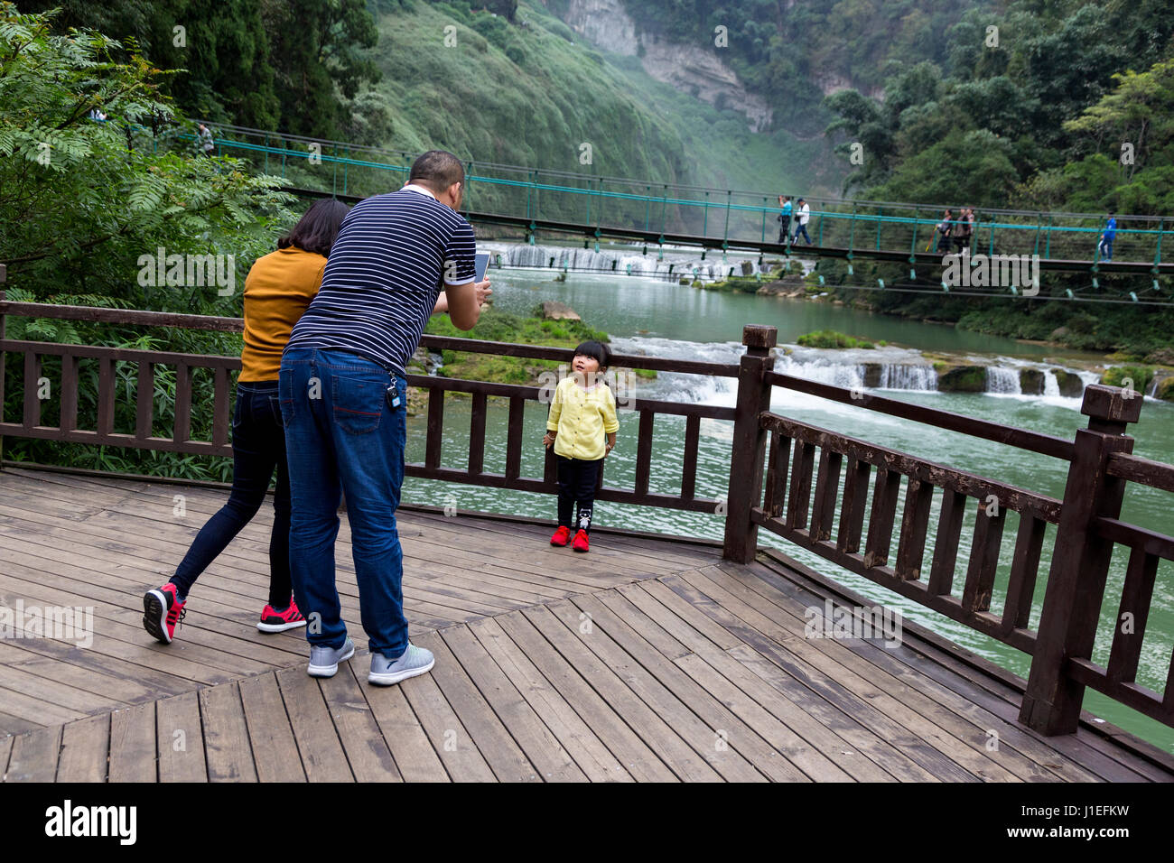 Guizhou, Cina. I genitori di fotografare la loro figlia a frutto giallo Tree (Huangguoshu) Cascata Scenic Area. Foto Stock