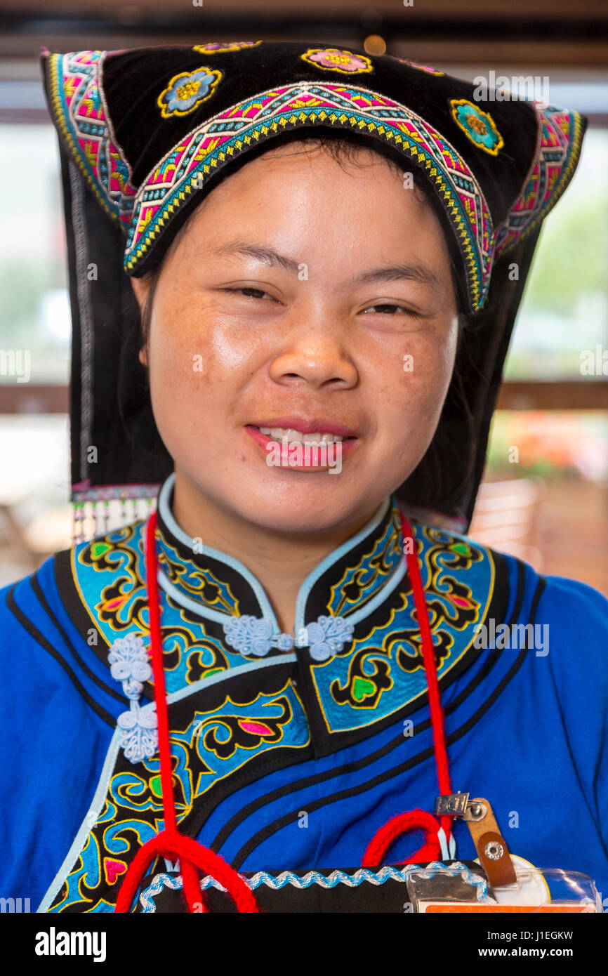 Guizhou, Cina. Han giovane donna cinese in abito Bouyei, lavorando in una banchina di riposo. Foto Stock