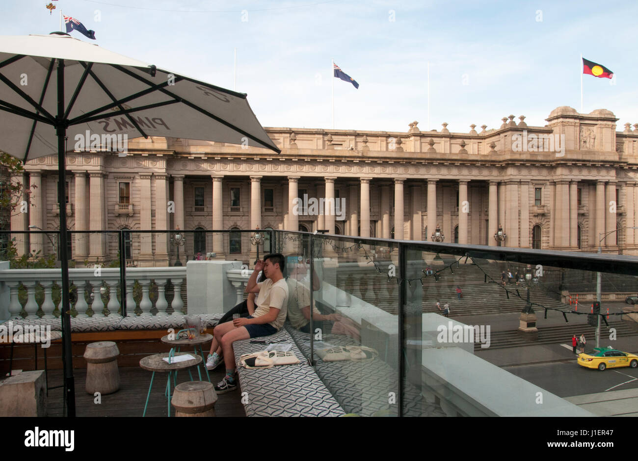 Patroni presso un bar sul tetto che si affaccia sul Parlamento vittoriano su Spring Street, Melbourne, Australia Foto Stock