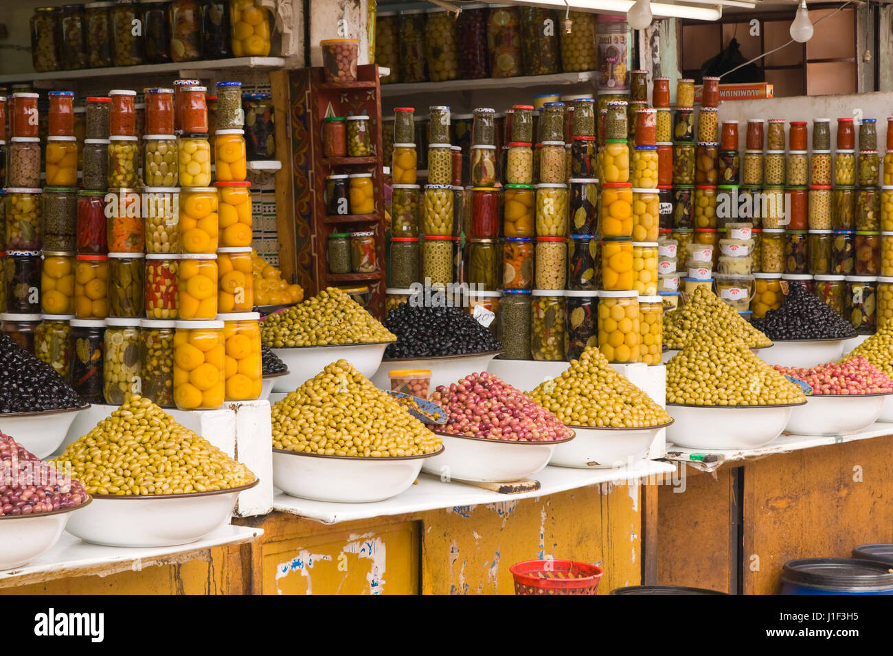 Pressione di stallo di mercato la vendita di olive fresche e prodotti alimentari in bottiglia nella principale souk di Marrakech, Marocco. Foto Stock