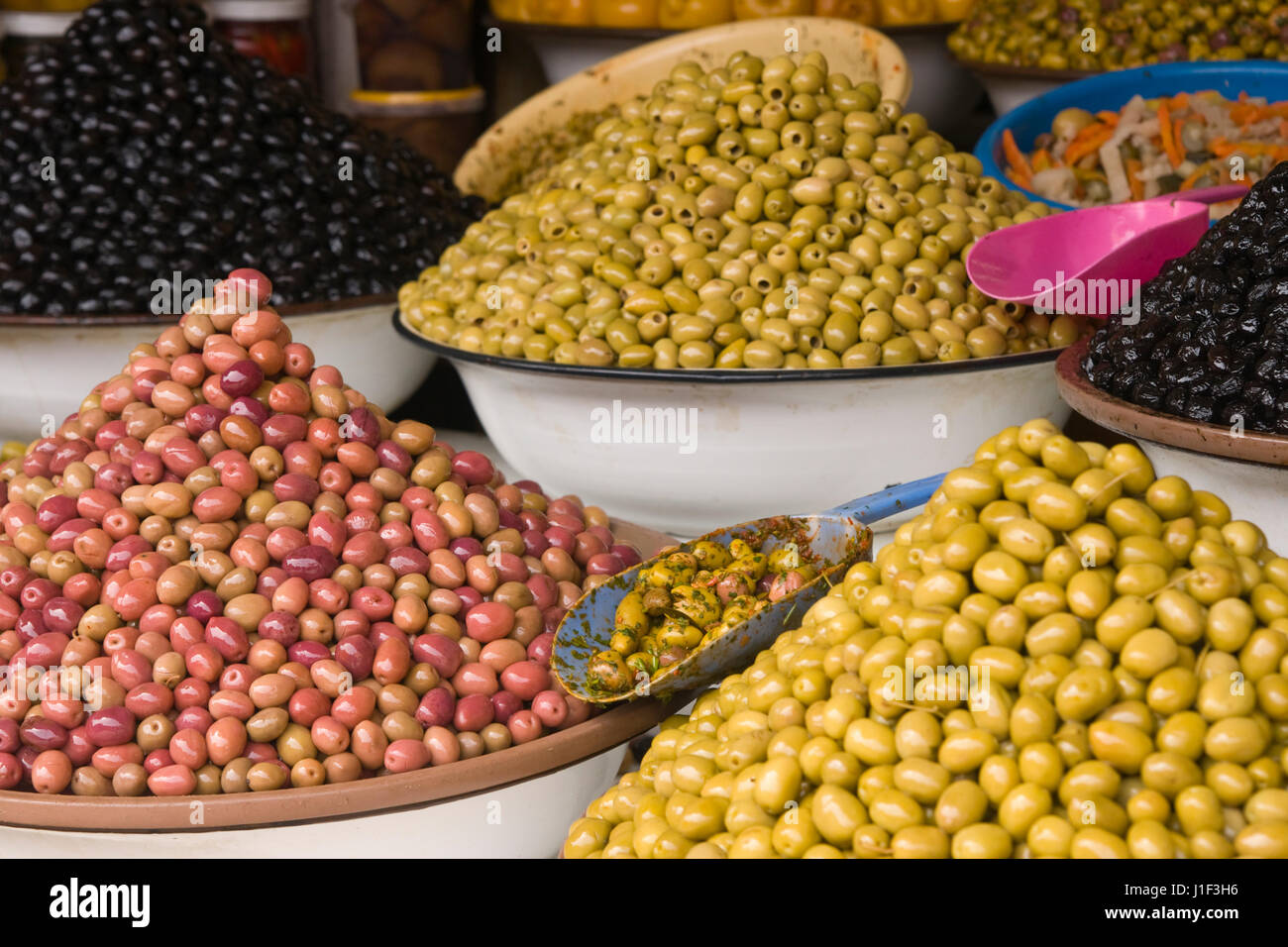 Pressione di stallo di mercato la vendita di olive fresche e prodotti alimentari in bottiglia nella principale souk di Marrakech, Marocco. Foto Stock