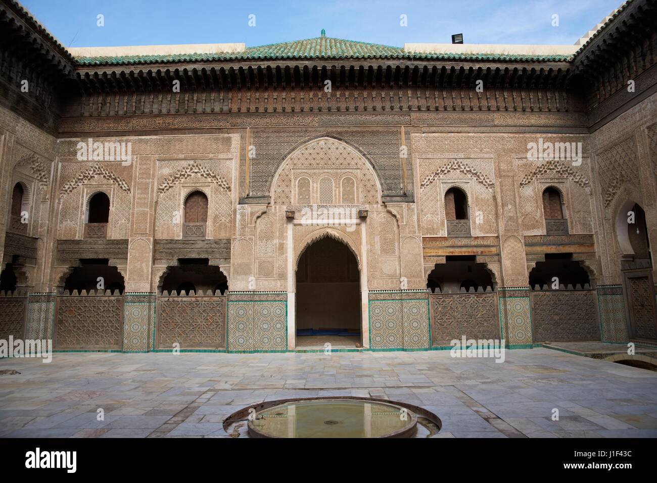 Carving ornati sulle pareti intonacate e sul lavoro di legno nel cortile della storica Madrasa Bou Inania nell'antica medina di Fes in Marocco. Foto Stock