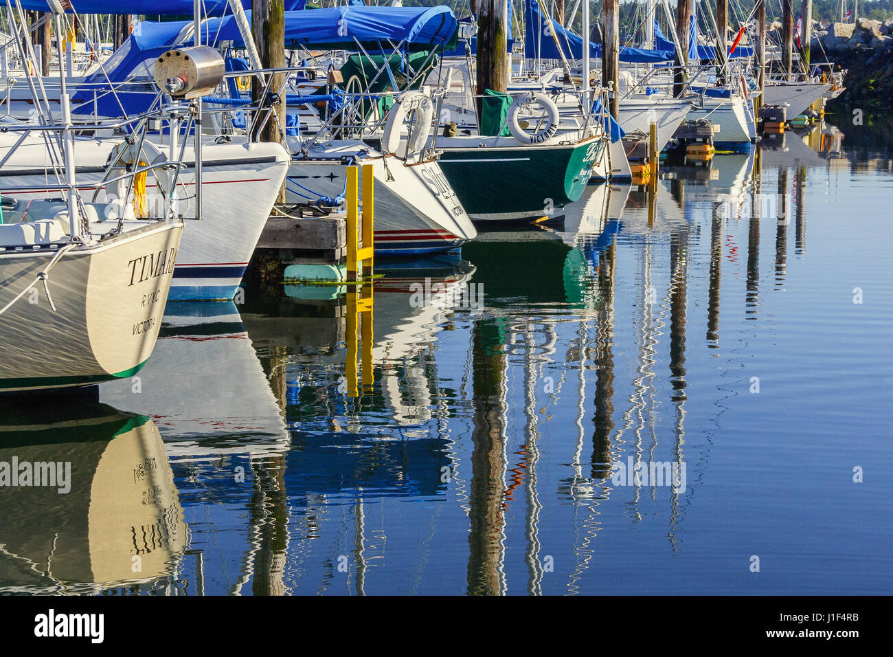 Barca a vela Scafi sono riflessi nell'acqua di uno yacht club marina su una soleggiata mattina d'estate. Foto Stock