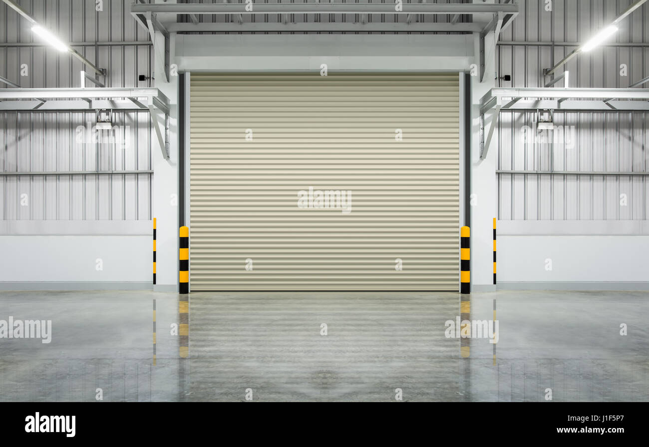 Sportello o rullo porta e pavimento di cemento all'interno di edificio in fabbrica per uso industriale. Foto Stock