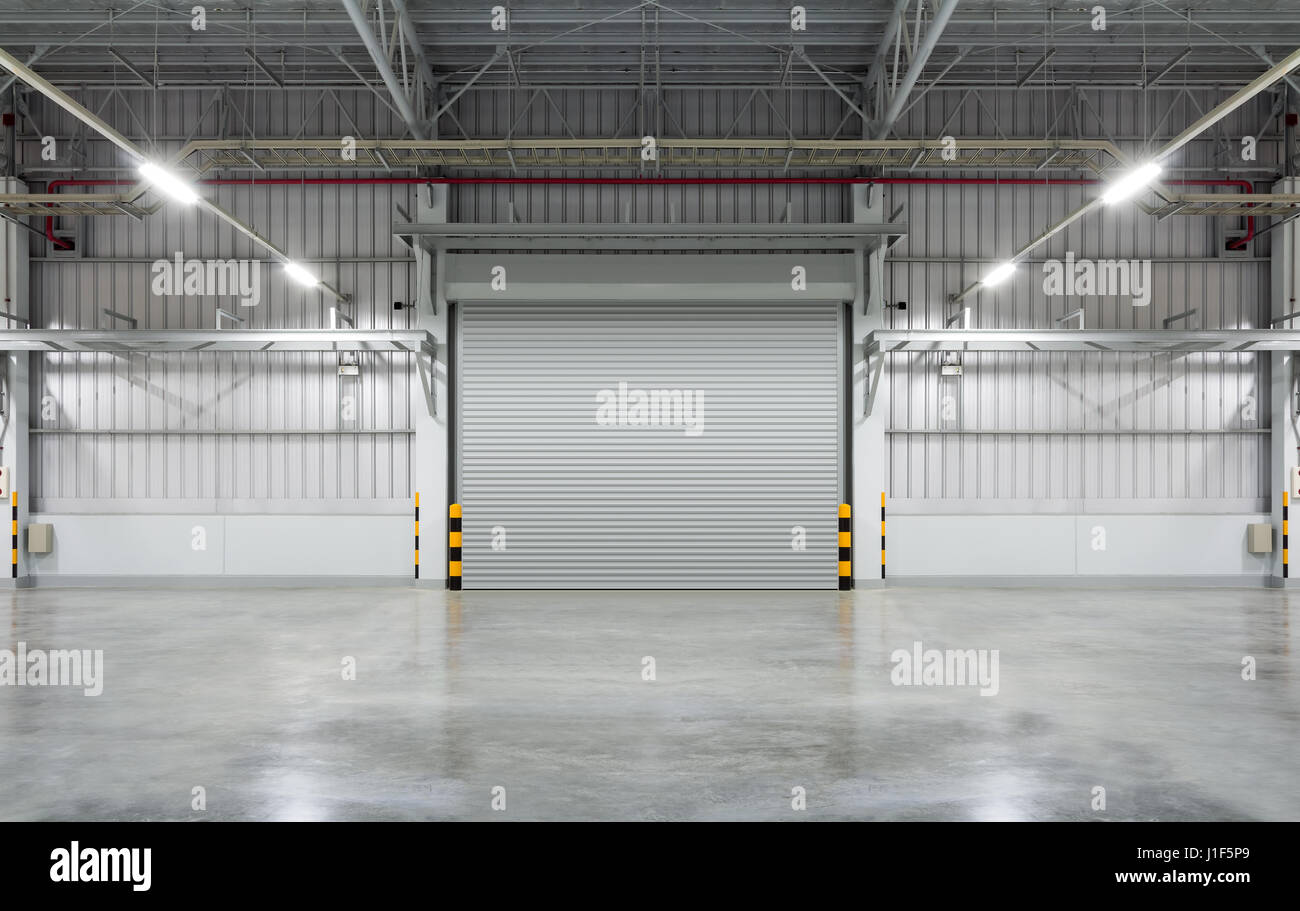 Sportello o rullo porta e pavimento di cemento all'interno di edificio in fabbrica per uso industriale. Foto Stock
