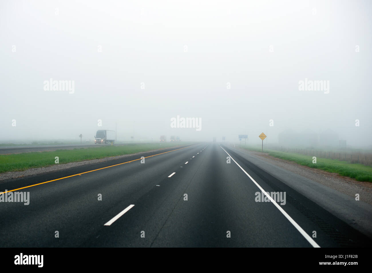 Il convoglio di camion semi di vari modelli e marche di latte fog-inzuppato dritto interstate highway line separato il traffico in avvicinamento Foto Stock