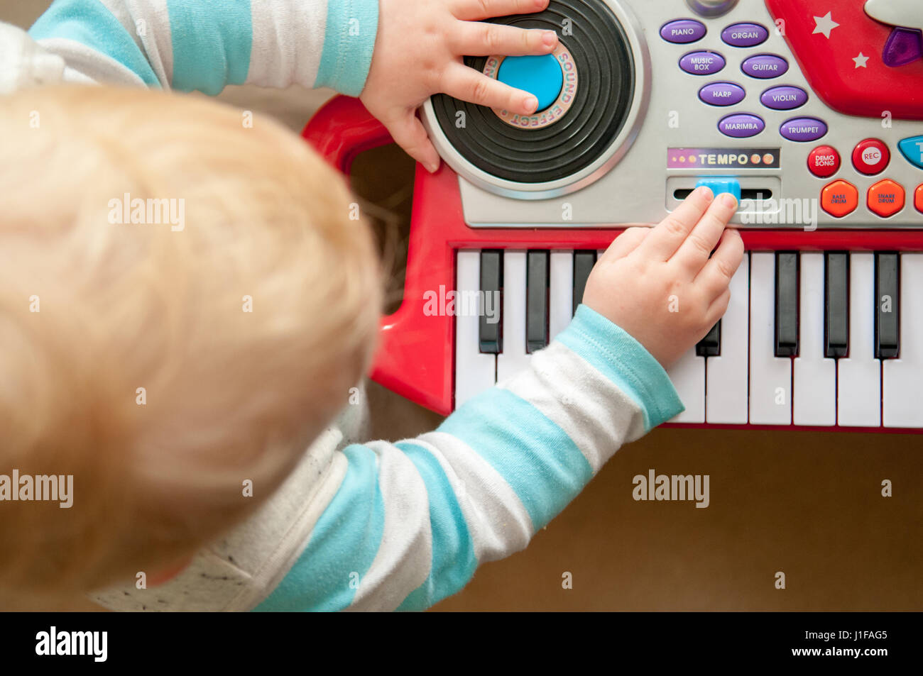 Giovane ragazzo giocando con uno strumento musicale giocattolo a casa Foto Stock