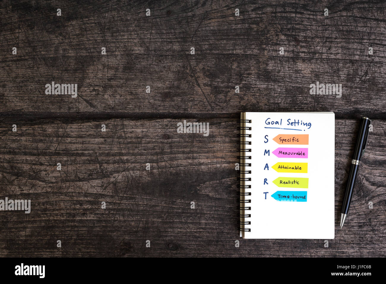 La grafia impostazione obiettivo smart il notebook aperto con la penna sulla grungy scrivania in legno, la concezione di business Foto Stock