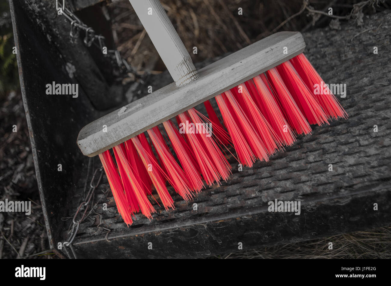 Scopa in legno con setole rosso in piedi sul ferro arrugginito scale Foto Stock
