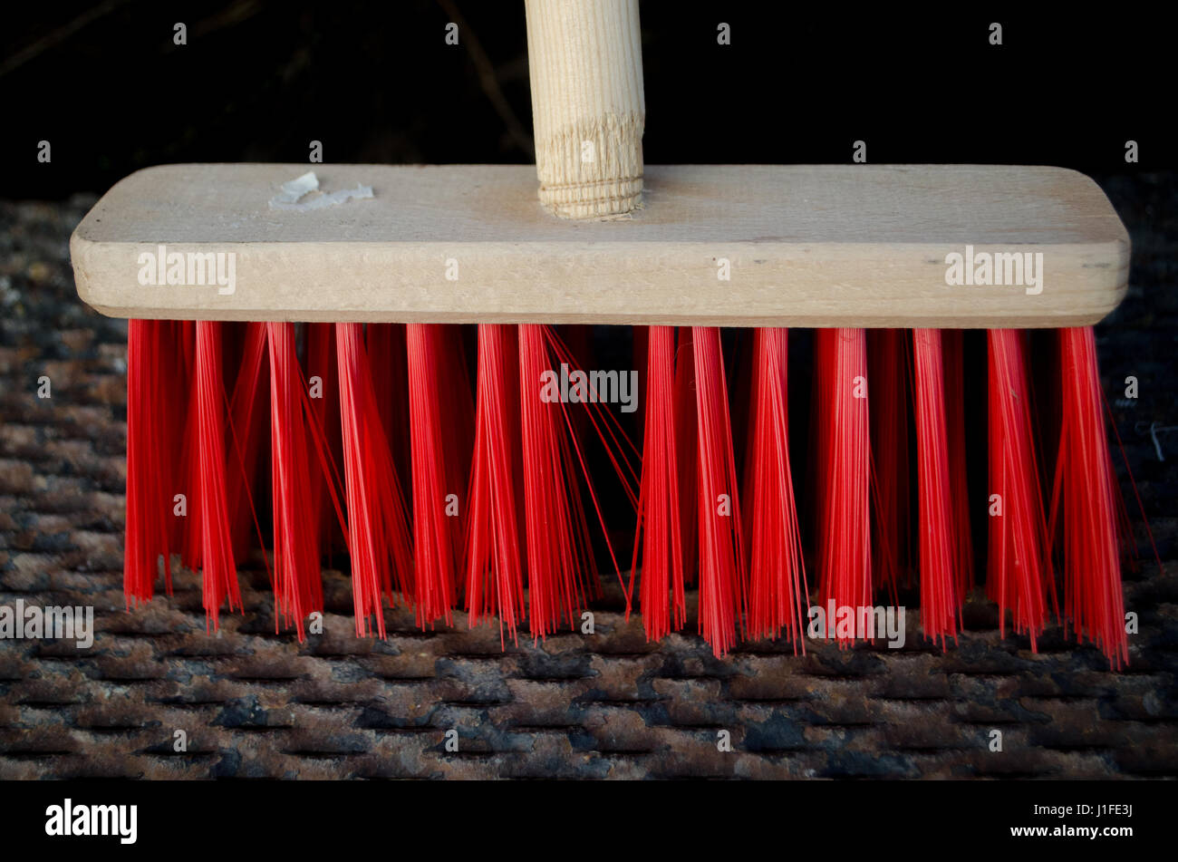 Scopa in legno con setole rosso in piedi sul ferro arrugginito scale Foto Stock
