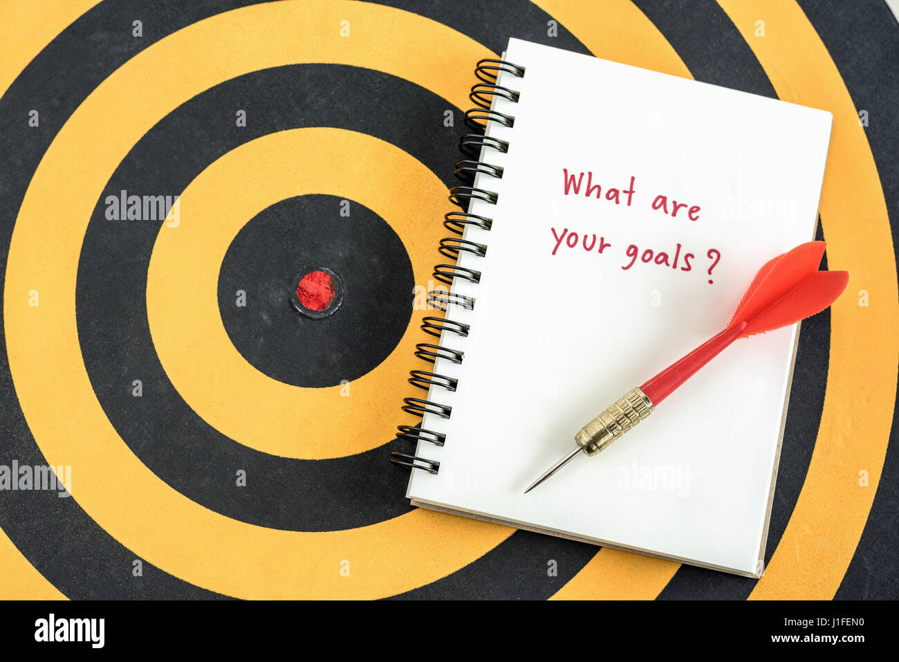 La grafia quali sono i vostri obiettivi in notebook con dart obiettivo sopra dartboard il successo del business concept Foto Stock
