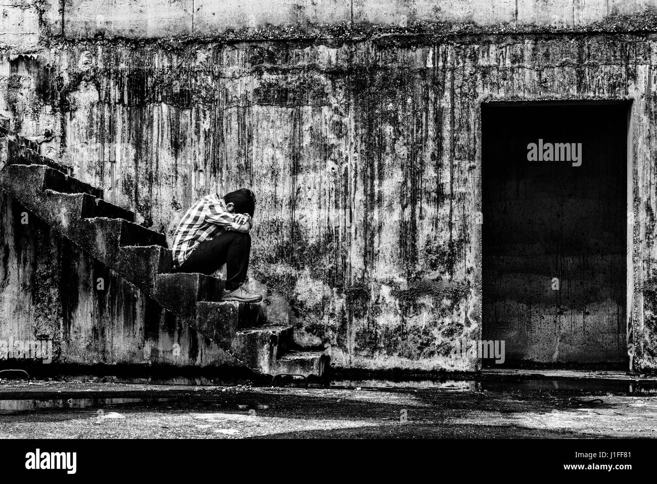 Premuto adolescente seduto sul gradino in creepy edificio abbandonato, concetto di oscurità Foto Stock