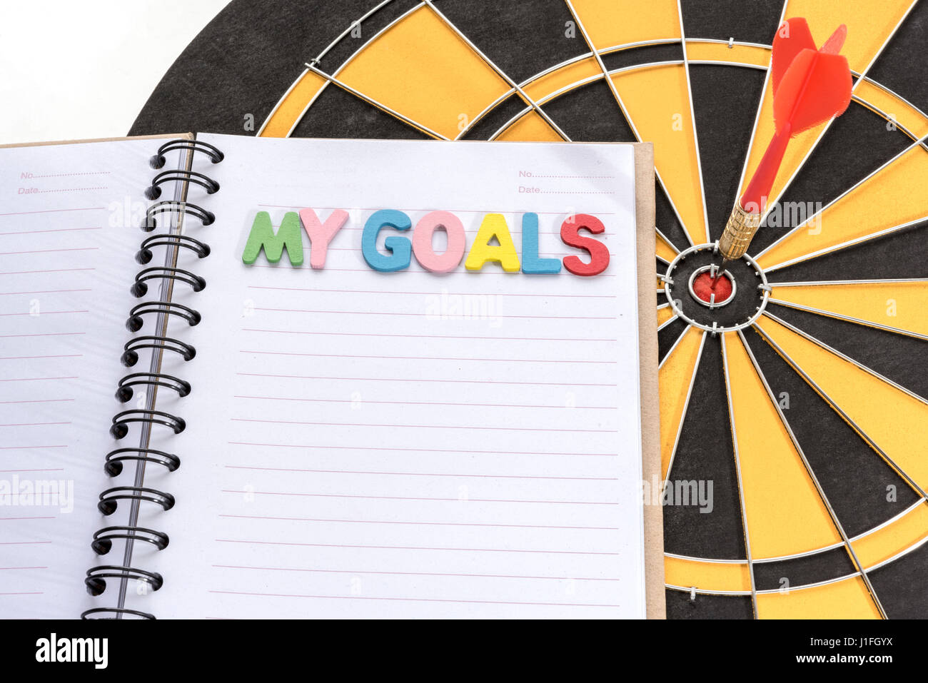 I miei obiettivi sul notebook di riciclo con dart su bullseye target in dartboard sfondo con spazio copia il successo del business concept Foto Stock