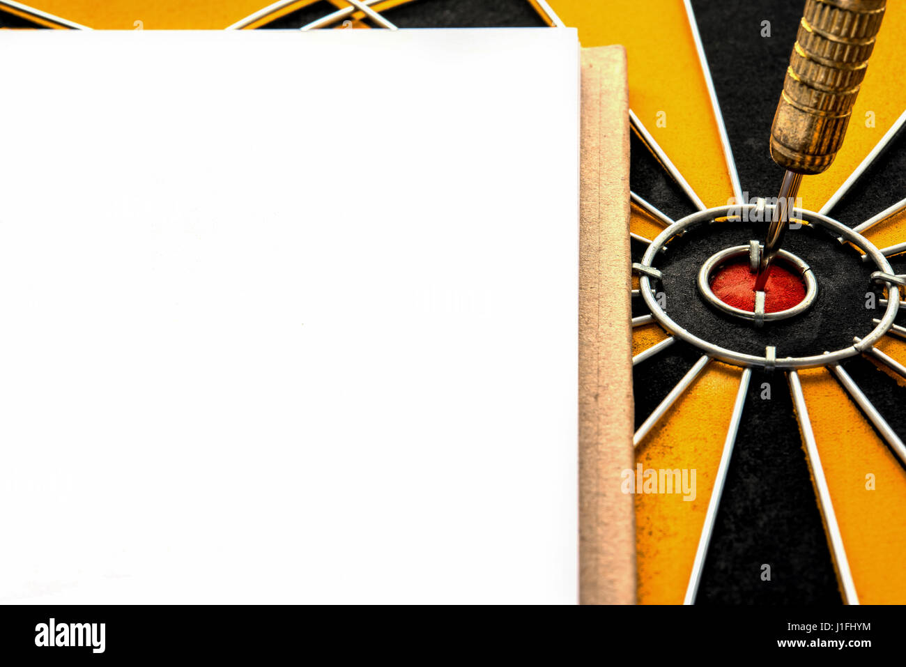 Closeup dart destinazione con la freccia sul centro di dartboard e notebook con copia spazio, obiettivo di destinazione il successo degli investimenti aziendali strategia finanziaria con Foto Stock