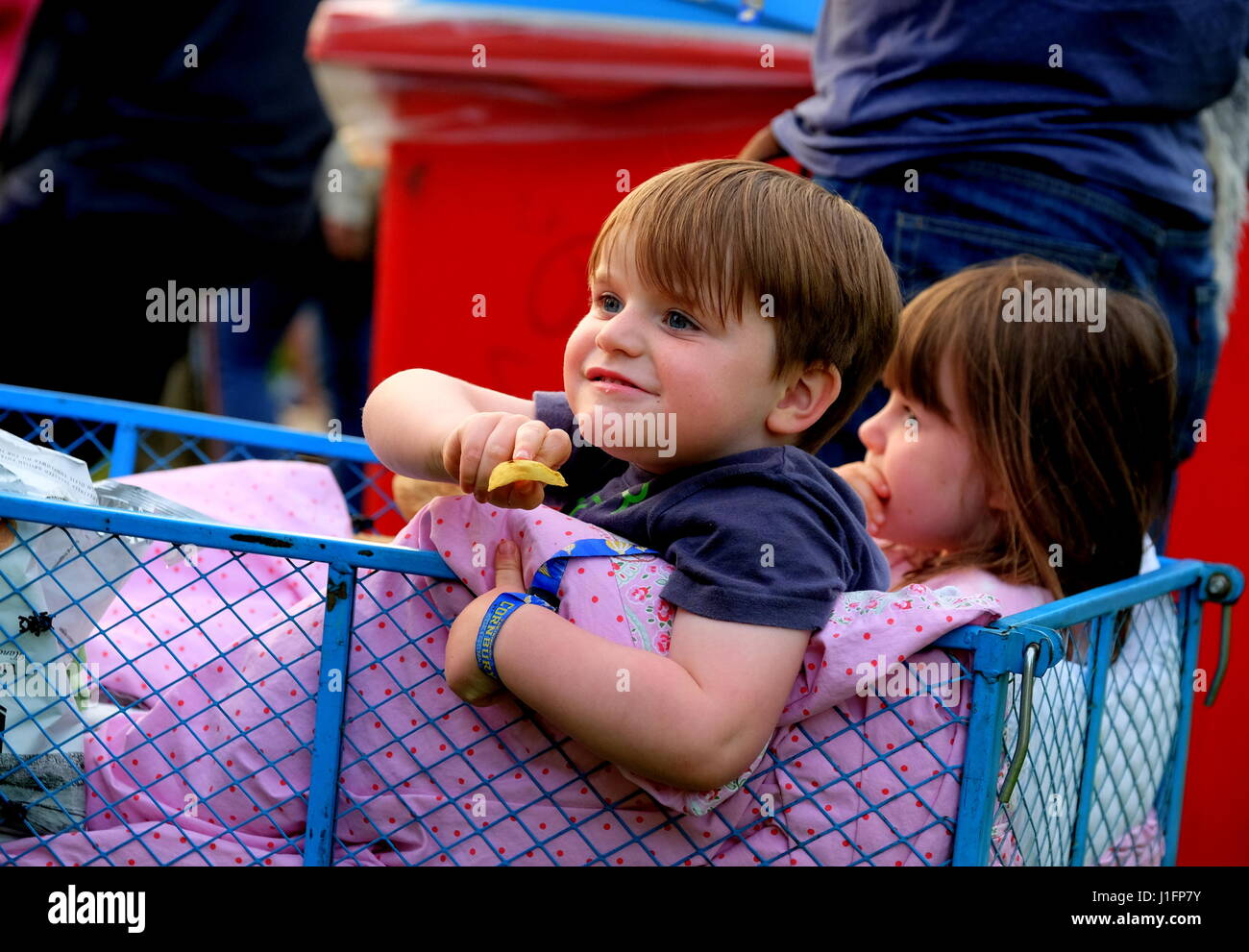 Due giovani figli godendo di seduta in un carro guardando la musica dal vivo al festival Cornbury Foto Stock