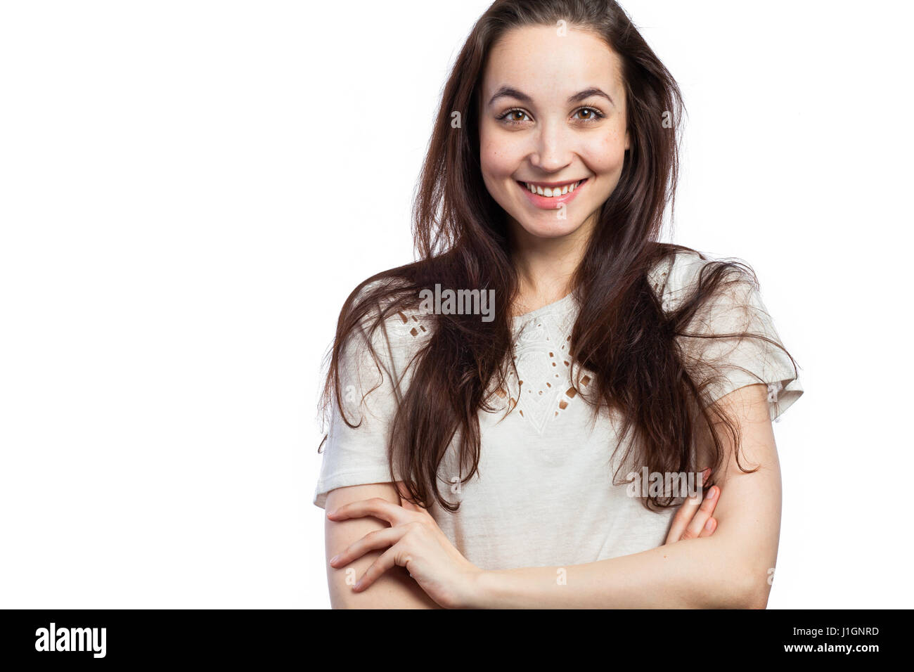 Ritratto di una giovane donna sorridente guardando rilassato e fiducioso, con le braccia incrociate, isolato su bianco Foto Stock
