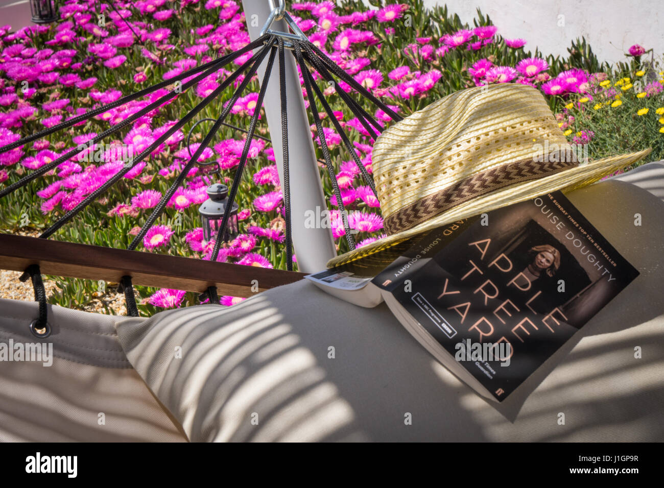 Amaca al sole con un libro in brossura e cappello per il sole Foto Stock