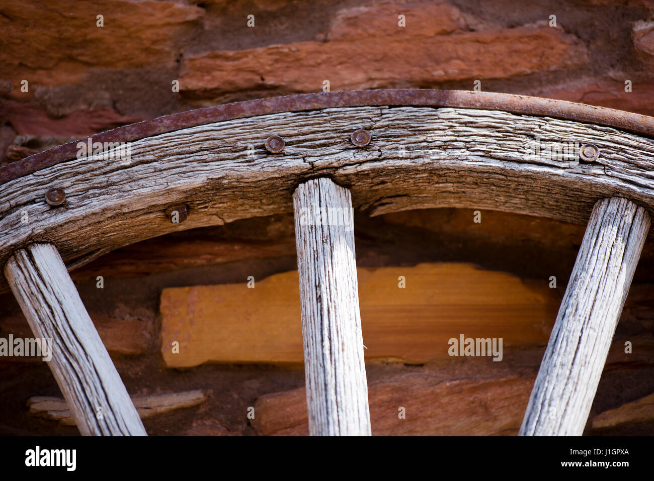 Dettaglio di un vecchio retrò ruota in legno con metallo arrugginito cerchio sullo sfondo di un muro di pietra costruito Foto Stock