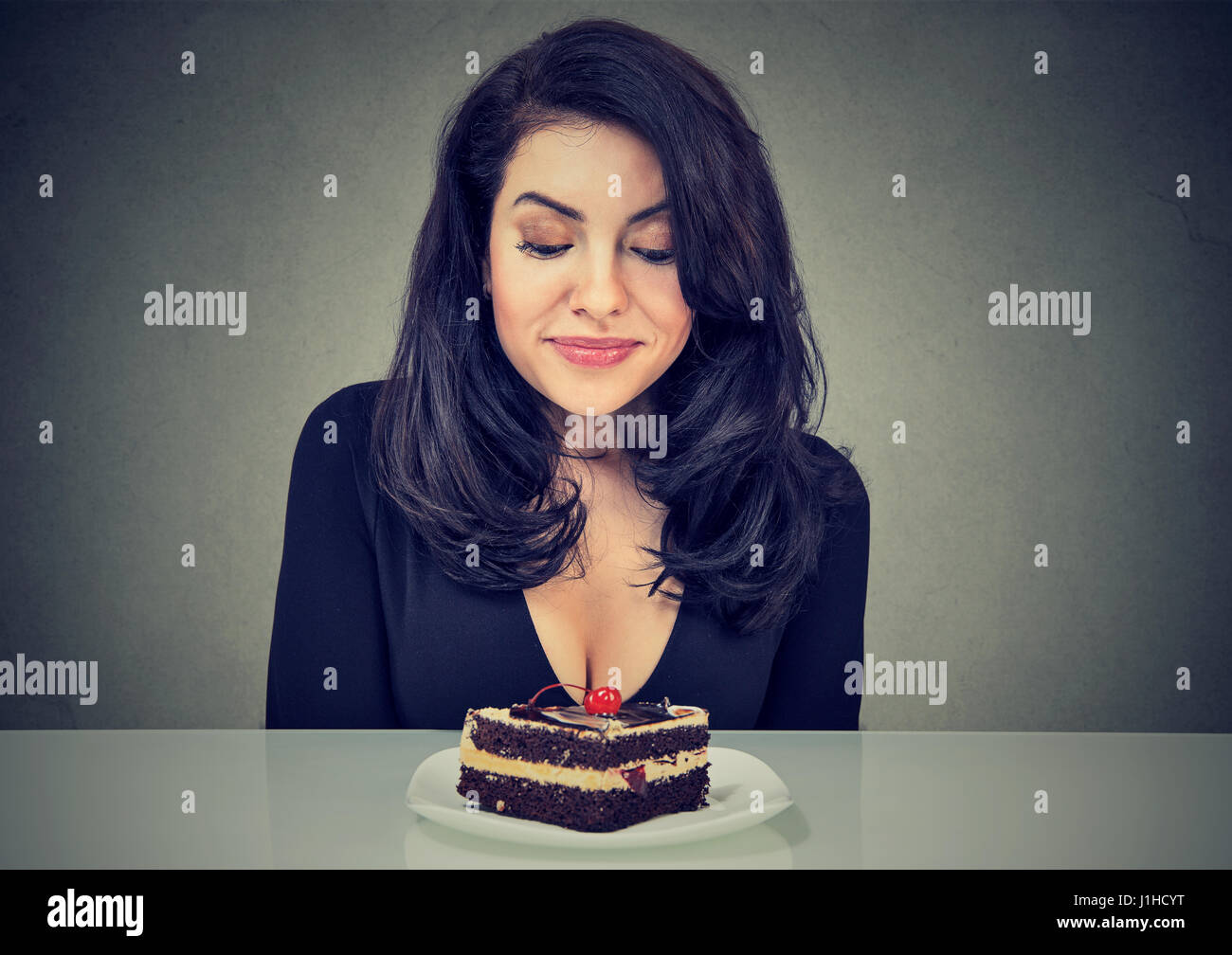 Donna disperata voglia dessert torta, desiderosi di mangiare, isolata su uno sfondo grigio Foto Stock