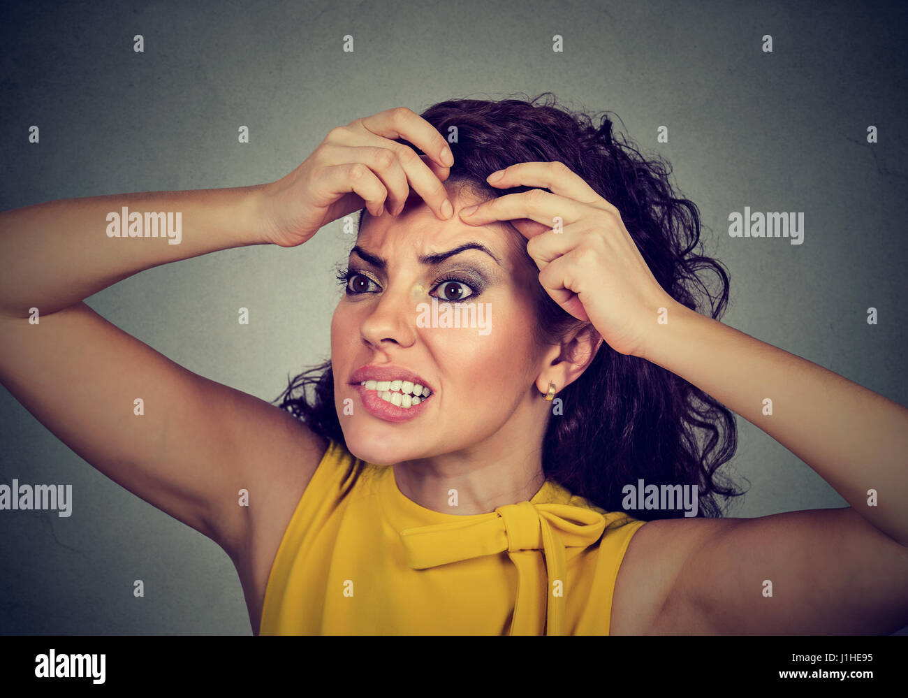 Closeup ritratto di una donna che guarda in uno specchio la spremitura di un acne o blackhead sulla sua faccia fronte Foto Stock