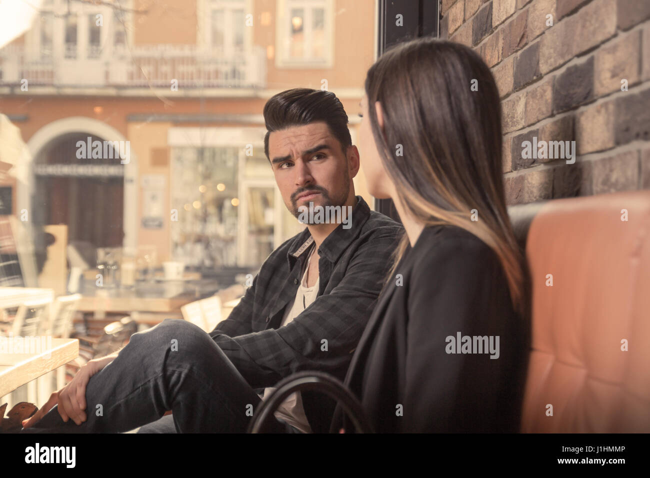 I giovani adulti 20s, uomo donna, arrabbiato cercando faccia espressione, torna in interni cafe Foto Stock